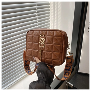 Close-up of brown quilted shoulder bag with gold hardware tassel and colorful wide strap