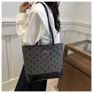 Close-up of gray canvas tote bag featuring black polka dots and silver bow charm detail