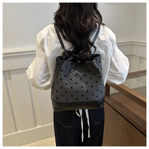 Detailed back view of a grey polka dot canvas backpack with a silver bow charm