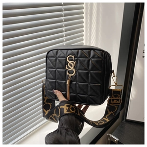 Detail of black quilted shoulder bag featuring gold SS logo and elegant tassel charm