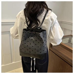 Detail view of grey polka dot backpack with silver bow hardware and durable black base
