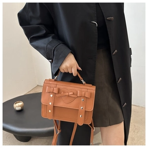 Close-up of vintage brown bag featuring heart stitching and decorative bows