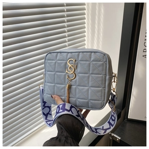 Detail of light blue quilted crossbody bag featuring golden hardware and wide strap