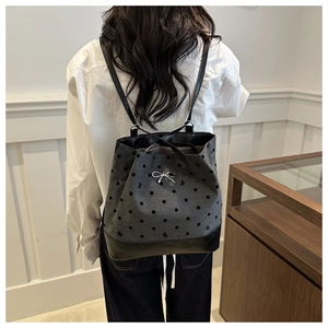 Polka dot canvas tote bag with black leather straps and silver bow pendant on model