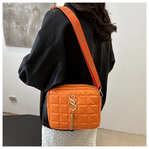 Detail of orange quilted crossbody bag with gold logo, fringe and printed wide strap
