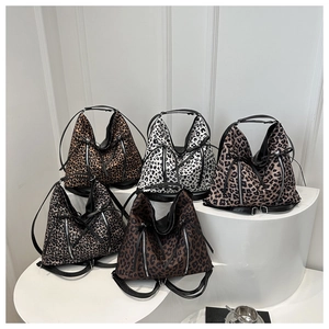 Cinco bolsos tote con estampado de leopardo en varios colores sobre un podio blanco