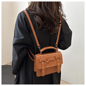 Detail of brown leather backpack with heart embroidery and metallic studs on the back
