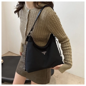 Detail of the black nylon hobo bag with a chain strap and metal triangle logo plaque