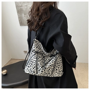 Detail of leopard print tote bag with black bow and multiple zippers worn by model