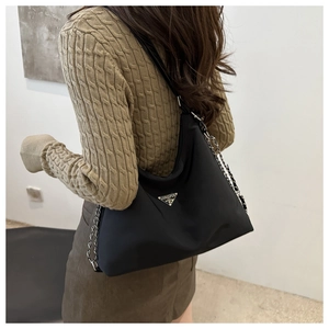 Detail of black nylon half-moon bag featuring silver chain strap and triangle metal logo