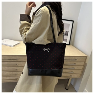 Close-up of heart pattern tote bag with silver bow detail and leather shoulder strap