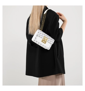 Gros plan d'un sac en cuir blanc avec imprimé floral rétro et chaîne dorée