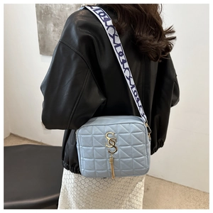 Detail of light blue quilted crossbody bag featuring gold hardware and a jacquard strap