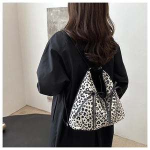 Detalle de mochila con estampado de leopardo, lazo negro y cremallera metálica