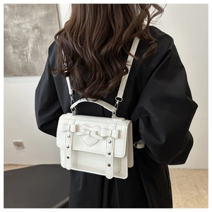 Close-up of white leather backpack with heart embossing, bow detail, and silver rivets