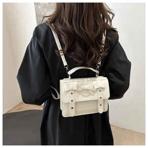 Detalle de mochila de cuero blanco con relieve de corazón y lazo decorativo suave