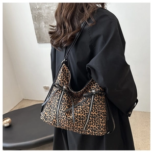 Detail shot of leopard print tote bag featuring black bow and vertical metal zippers