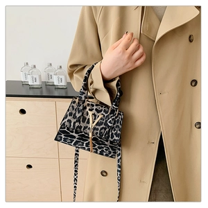 Dettaglio della borsa a tracolla leopardata con logo V dorato e nappa indossata con trench