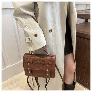 Close-up of brown vintage crossbody bag with bow accents and heart embossed detail
