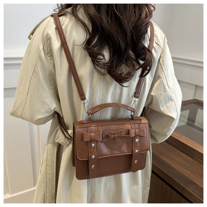 Detail of heart-embossed brown leather backpack with bow accent and metal studs