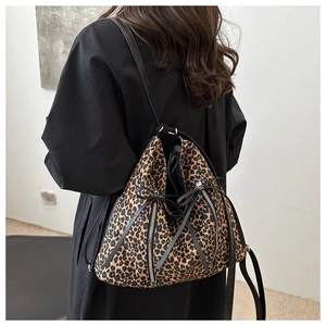 Detailed view of leopard print shoulder bag featuring bow ties and side zipper accents