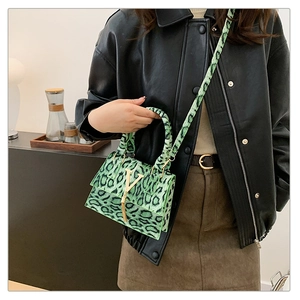 Dettaglio della borsa a mano leopardata verde con logo V dorato e frangia fine