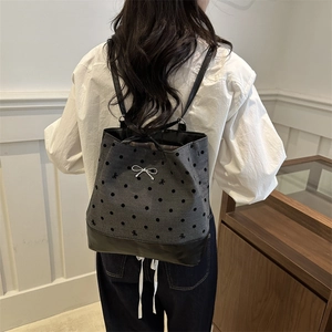 Chic grey polka dot backpack with white bow detail and black leather base on model