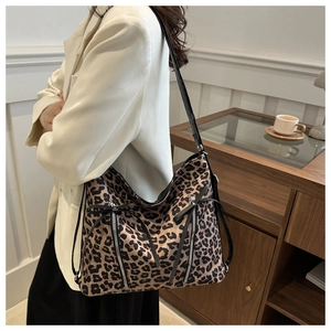 Detail view of leopard print shoulder bag featuring vertical zippers and leather straps