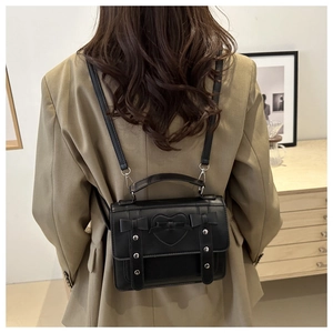 Model view of black leather backpack with heart and bow details in casual setting
