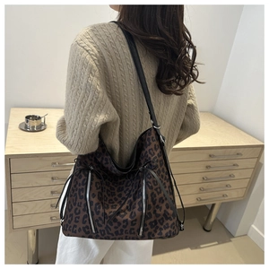 Primer plano del bolso tote de leopardo con cremallera plateada y correas de cuero negro