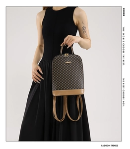 Detail of checkered backpack featuring brown faux leather straps and golden metal zippers