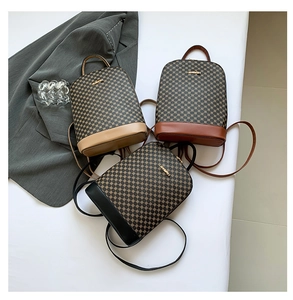 Detailed view of three mini backpacks in brown plaid with leather trim and metal logos