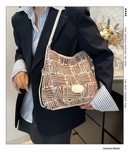 Detailed view of woven geometric pattern bucket bag with white leather strap and texture