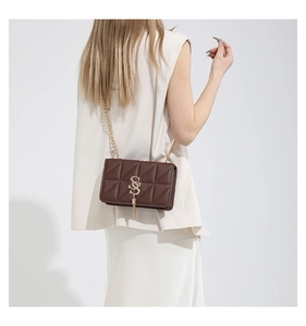 Close-up of brown quilted bag featuring gold interlocking hardware and tassel charm