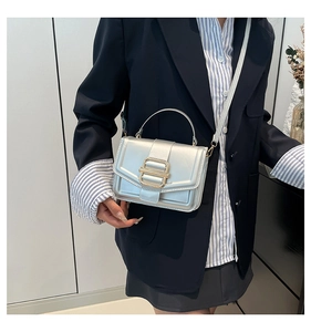 Silver leather crossbody bag with gold buckle shown worn by a model in a casual setting