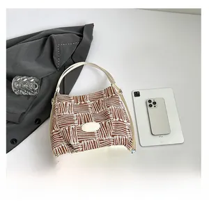 Vue à plat du cabas tissé géométrique avec base en cuir blanc et accessoires tech