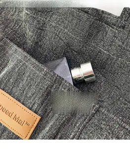 Detail view of a dark grey denim tote bag showing reinforced pockets and brown leather tag