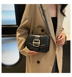 Close-up of black lychee grain leather crossbody bag with elegant gold buckle detail