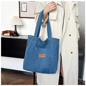 Detail of blue denim tote bag texture with brown brand leather patch and utility pocket