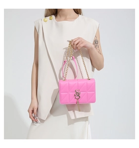 Detail of pink quilted bag with golden S-logo buckle and tassel on chain strap