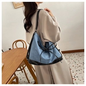 Detail of blue denim tote bag with black leather trim and chic bow tie decoration