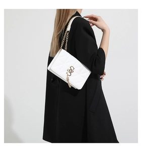 Detailed close-up of white quilted leather texture and gold chain strap on shoulder bag
