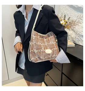 Brown and white woven check tote bag worn on shoulder in a cozy home interior setting