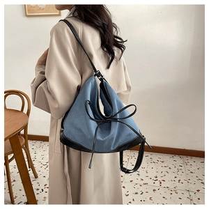 Detail of blue canvas tote bag with black leather trim and decorative bow knot