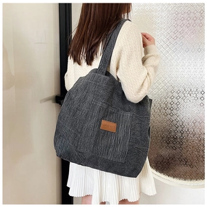 Detail of grey corduroy tote bag showing textured fabric and square leather logo patch