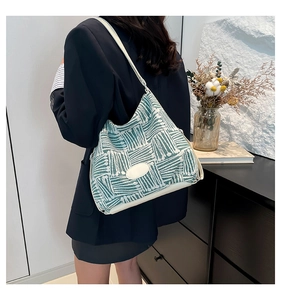 Detail of green knit tote bag with geometric stripes worn by model in minimalist setting