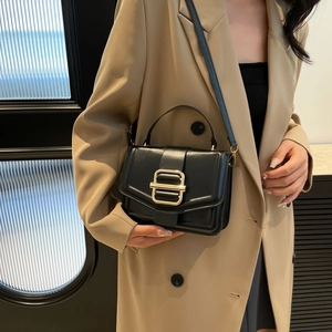 Elegant black leather crossbody bag with gold buckle shown on model in a modern office setting