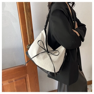 Detail of canvas tote bag with contrast leather trim and a chic bow decoration