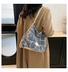 Detail of blue and white geometric pattern bucket bag worn with a khaki coat