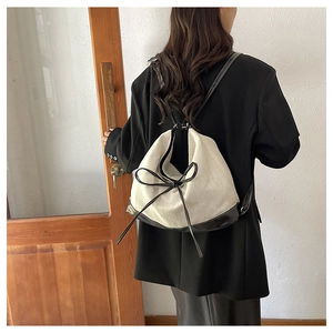 Detailed back view of a woman wearing the minimalist canvas backpack with black leather bow
